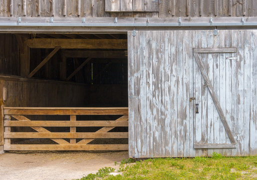 Rustic barn door open revealing animal stall and gate inside