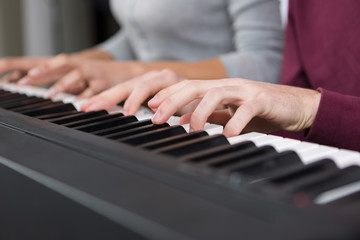 4 hands playing piano close up
