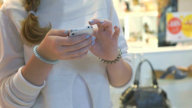 Girl holding silver smartphone and reads informational text. Close-up