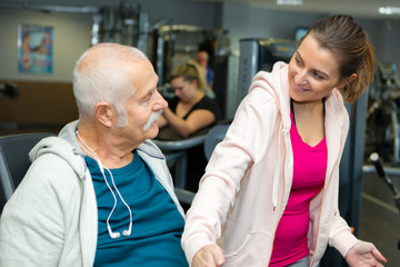 Obraz premium senior man and trainer exercising in gym