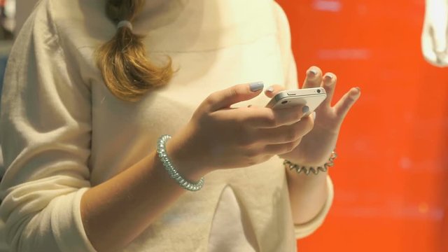 Girl holding silver smartphone and reads informational text. Close-up