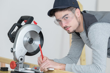 young carpenter using circular saw for wood inside warehouse