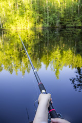 Fishing rod in the hands of the fisherman, close up, from the first person's view