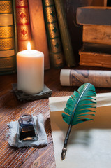 Quill pen, old papers and books by candle light