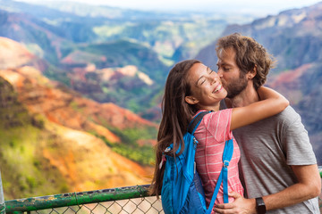 Couple in love kissing on nature travel hiking in Hawaii mountains. Young hikers people happy together. Interracial backpacking lovers kiss portrait on vacation hike.