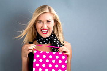 Happy young woman holding a shopping bag on a gray background