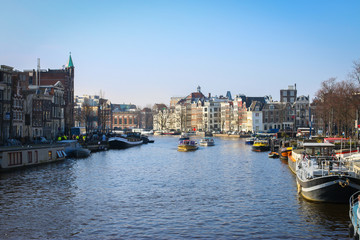 Fototapeta na wymiar Boats are cruising through the water canal in Amsterdam city during the day