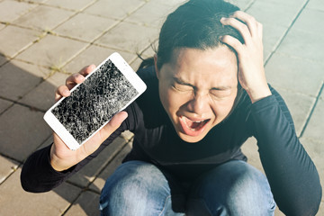 Screaming woman  holding a screen crack the smartphone outdoor. - 162189077