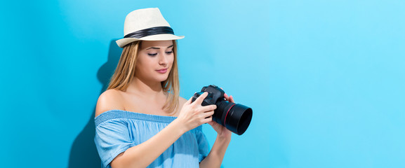 Young woman holding a camera on a blue background