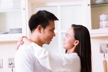 Asian Woman is hugging man in kitchen
