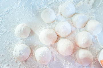 Ball of pizza dough on a white background with dusting of flour.White flour with dough in a bakery from top view. Bakery Concept.