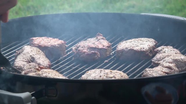 Man's hands cooking steak on grill