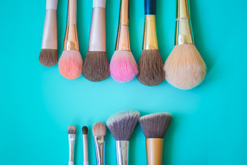 Set of decorative cosmetics and brushes on Green background.