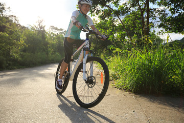 woman cyclist cycling on sunrise forest trail