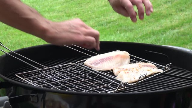 Man's hands cooking fish fillet on grill