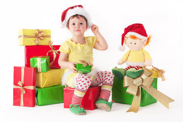 Little girl sitting on pipe of presents with a toy hob on chrismas isolated on white background
