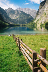 Fototapeta na wymiar Two travellers sitting near alpine lake with spectacular mountains view