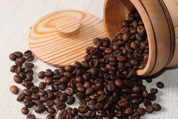 Coffee beans scattered from a Cup on white wooden background, wooden utensils,