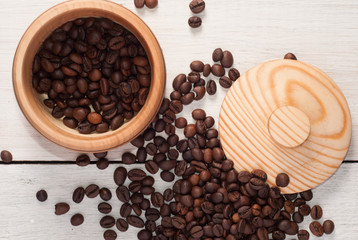 A wooden bowl with coffee beans on old wooden table,