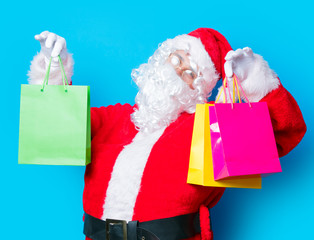 Funny Santa Claus have a fun with shopping bags on blue background