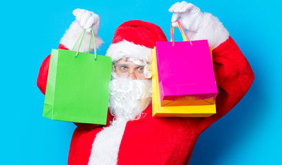 Funny Santa Claus have a fun with shopping bags on blue background
