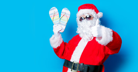 Fototapeta na wymiar Funny Santa Claus have a fun with vacation flip flops