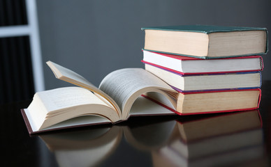 Open book and hardcover books on wooden table in library. Education background.