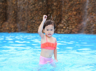 Naklejka premium Pretty little girl playing in swimming pool outdoors.