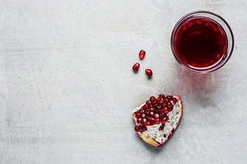Red pomegranate and juice in a class on a grey concrete background