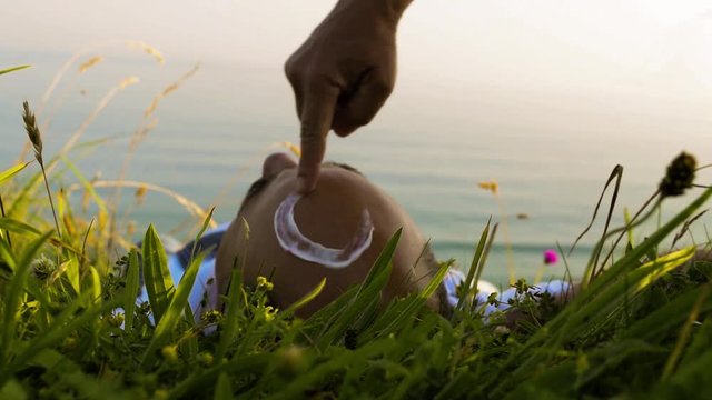 Femme dessine le soleil sur le front d'un homme.