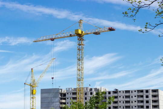 Two tower cranes against of multi-story residential building construction