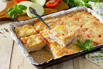 Baked zucchini with meat, rice, tomatoes and cheese on a wooden kitchen table.