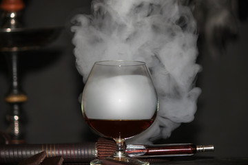 Heavy hookah smoke with a brandy glass on a gray background, hookah tube
