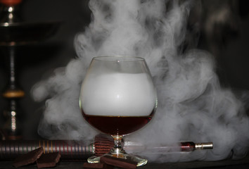 Heavy hookah smoke with a brandy glass on a gray background, hookah tube