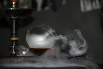 Heavy hookah smoke with a brandy glass on a gray background, hookah tube