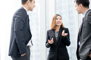 Asian businesswoman talking with her team in office building hallway