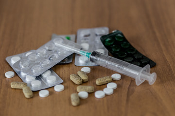 Medical syringe on table with some pills