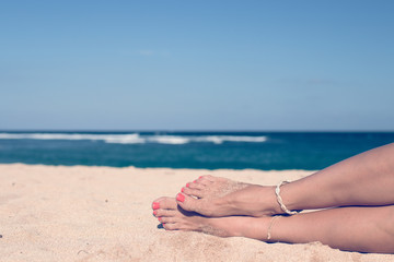 Tanned sexy legs of a woman against the sea. Tropical island Bali, Indonesia.