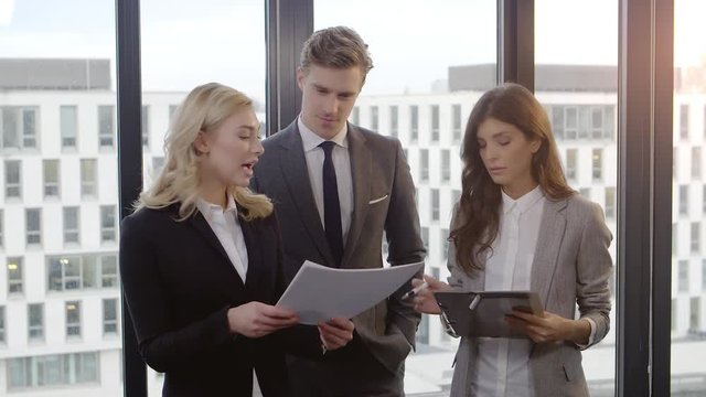Business meeting of three people against office Window. Shot with a Red dragon in 4K down convert to HD