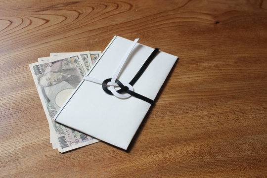 木の机の上に置かれた日本の不祝儀袋と現金