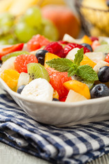 Delicious fruit salad with fresh fruit. Wooden, gray table in the background.