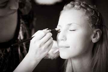 Obraz premium Beautiful girl put makeup on her face in a beauty salon