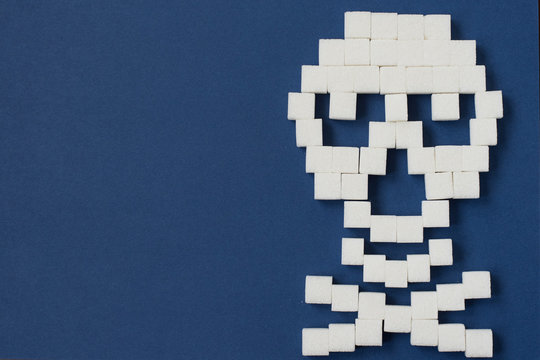 The skull made from sugar cubes. Sugar Kills. Blue background. diabetes concept. Suggesting dieting concept. Unhealthy white sugar concept. Copy space. Space for text.