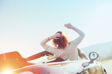 Young woman resting in a convertible at sunset enjoying the view