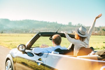 A loving couple rushing on a convertible enjoying the view