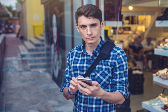 Man traveler looking at his smartphone on the background of the streets of the city