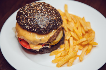 Black Burger on white Plate Served with french fries.