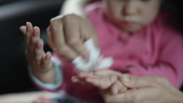 Woman wipes with a damp cloth hand your child sitting in the car. Closeup