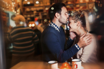 Happy couple kissing at bar and having date