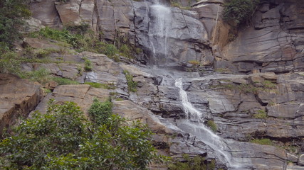 Rushing waterfall in the mountains with tropical forest. Beautiful nature background. Close up